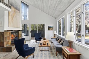 Ein geräumiges Wohnzimmer mit Kamin, großen Fenstern und moderner Einrichtung.