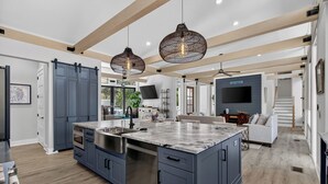 A modern kitchen with a large island, built-in appliances, and pendant lighting. - Private Pool + Outdoor Lounge + Movie Room + Game Room | Summerset by AvantStay (Isle Of Palms)