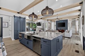 A modern kitchen with a large island, built-in appliances, and pendant lighting.