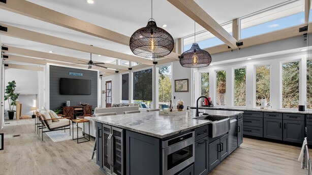 A spacious kitchen with a large island, dark cabinetry, and pendant lighting. - Private Pool + Outdoor Lounge + Movie Room + Game Room | Summerset by AvantStay (Isle Of Palms)