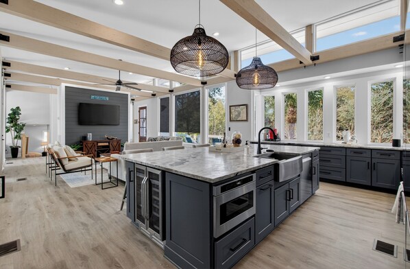 A spacious kitchen with a large island, dark cabinetry, and pendant lighting.