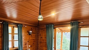 Ein Zimmer aus Holz mit einem Bett, Vorhängen und einem Fenster.