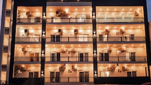 A multi-story hotel with balconies, air conditioning units, and a uniform exterior design. - Alpine Retreat (Rishikesh)
