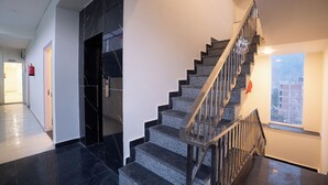 A modern interior with a staircase, a black marble wall, and a window with a view. - Alpine Retreat (Rishikesh)