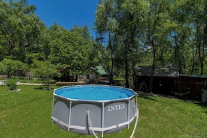 An outdoor swimming pool with a metal frame and a blue interior, surrounded by a grassy yard and trees. - Vacation home with whirlpool in Croatia (Breze)