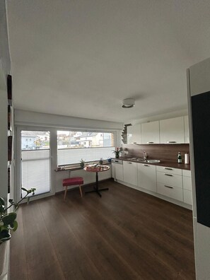Eine moderne Küche mit weißen Schränken, einer Holz Arbeitsplatte und einer roten Bank.
