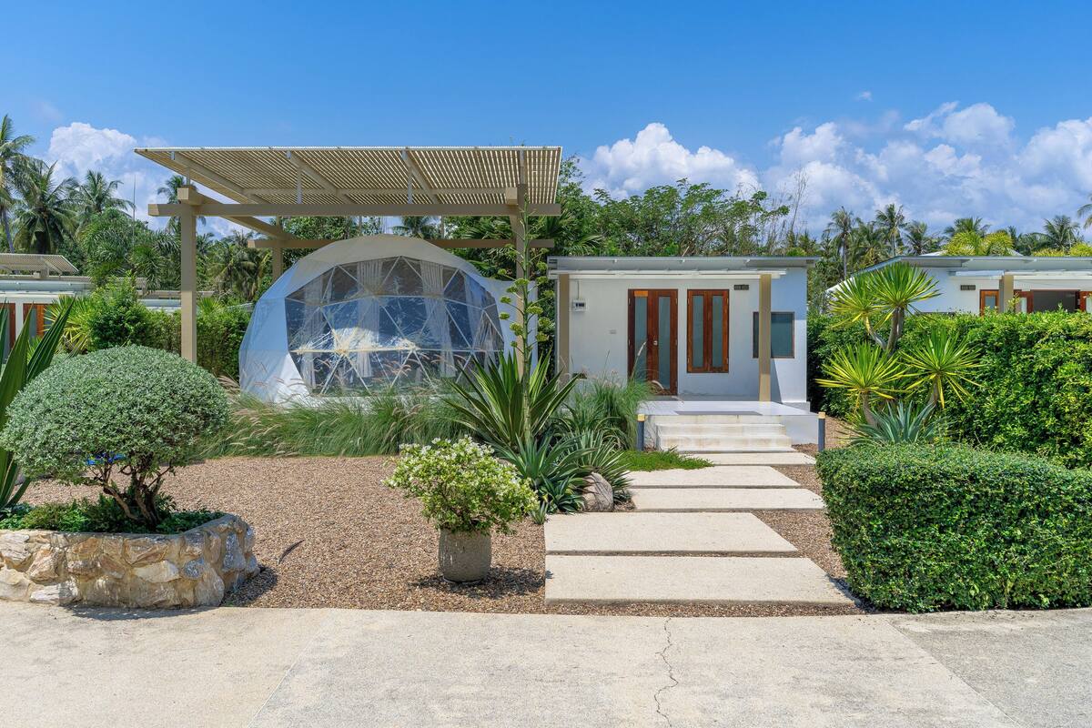 A resort with a dome structure, a covered walkway, and well-maintained gardens.