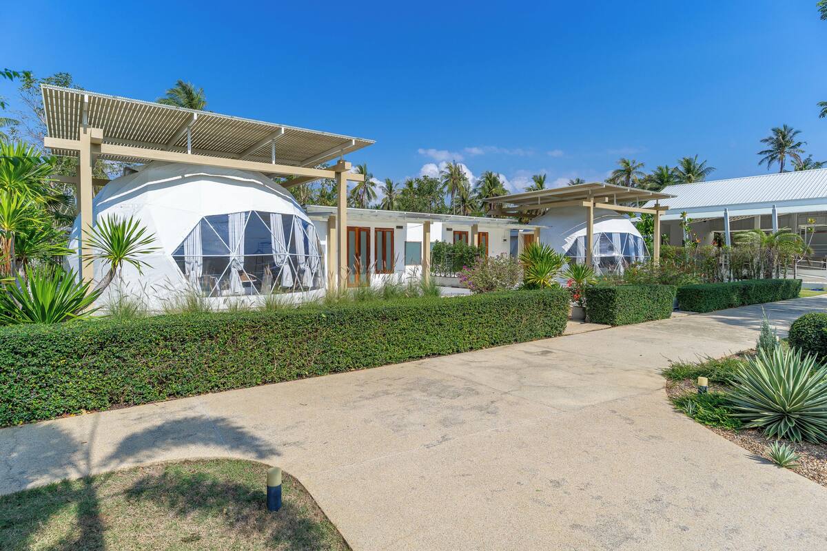 A resort with dome-shaped buildings, a paved walkway, and tropical landscaping.