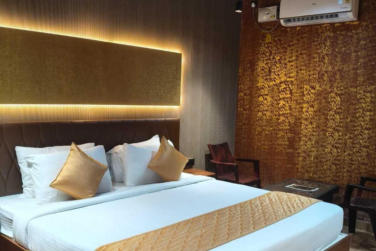 A modern hotel room with a large bed, a wooden headboard, an air conditioning unit, and a textured wall.