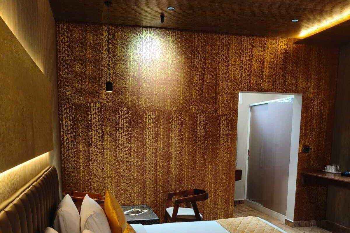 A hotel room with a large bed, a wooden headboard, a small table, and a door.