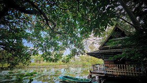 A tranquil pond with a wooden boat docked at a traditional wooden structure. - Tranquility living in the garden ,20km from airport (ฉะเชิงเทรา)