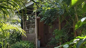 Um jardim com degraus que levam a uma porta de madeira, cercado por vegetação exuberante.