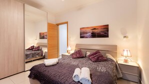 A bedroom with a bed, a nightstand, a mirror, and a painting on the wall. - Sliema Bluemist near Balluta Bay (Sliema)