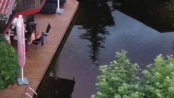 Un muelle se adentra en una masa de agua, con un edificio de techo rojo y mesas al aire libre.