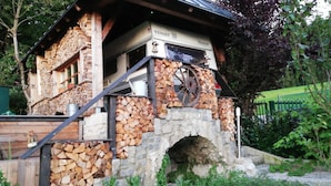 Um edifício de pedra com chaminé, escada de madeira e placa de metal.