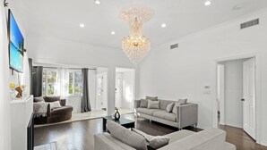 A spacious living room with a chandelier, sofas, and a flat-screen TV. - Beverly Hills Home • Guest House & Hot Tub (Beverly Hills)