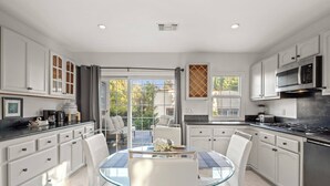 A modern kitchen with white cabinetry, a glass dining table, and a view of the outdoors. - Beverly Hills Home • Guest House & Hot Tub (Beverly Hills)