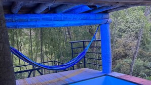 Un bain à remous avec une terrasse en bois et un hamac.