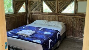 Une pièce en bois avec un lit, de grandes fenêtres et une vue sur la verdure environnante.