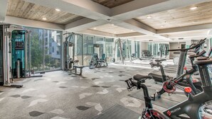 Ett gym med träningsutrustning, stora fönster och ett träpanelat tak.