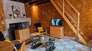 Una sala de estar tipo loft acogedora, con chimenea, muebles de madera, un televisor y una escalera.