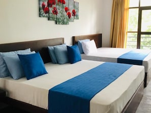 Two single beds with blue and white bedding, a wooden headboard, and a window with curtains. - RED LETTER HOTEL (Kandy Wattegama)