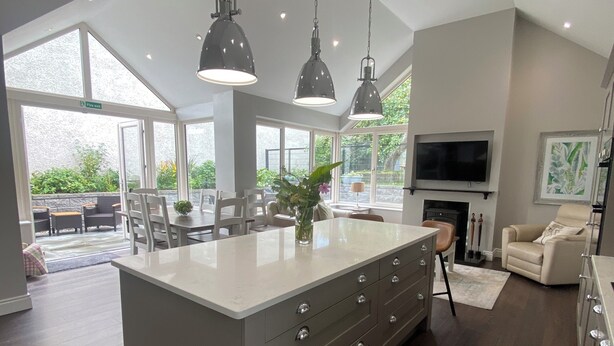 Una cocina amplia con una isla grande, iluminación colgante y vistas al exterior.