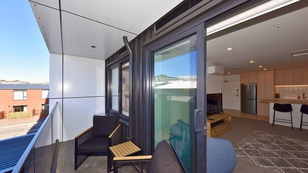 A modern apartment with a balcony, a dining area, and a kitchen. - Chic and Comfy 1 Bedroom in Manchester Street (Christchurch)
