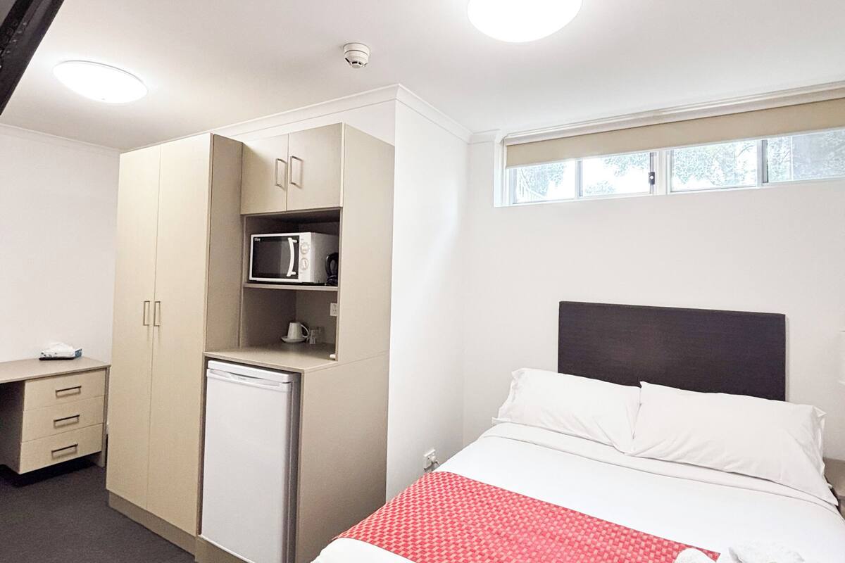 Une chambre d’hôtel avec un lit, une kitchenette, un bureau et une fenêtre.