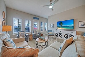 Ein Wohnzimmer mit Fernseher, Sofas, einem Couchtisch und einem Deckenventilator.