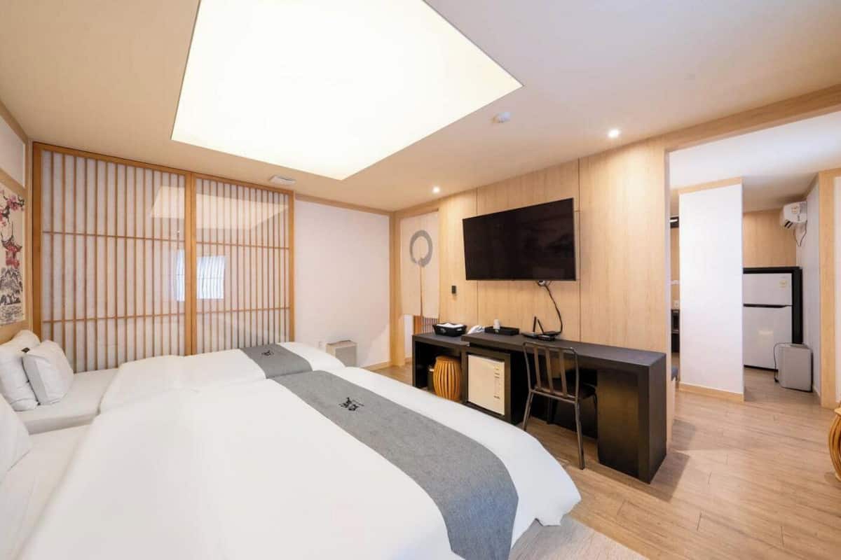 A modern hotel room with a large bed, a desk, a flat-screen TV, and a traditional Japanese shoji screen.