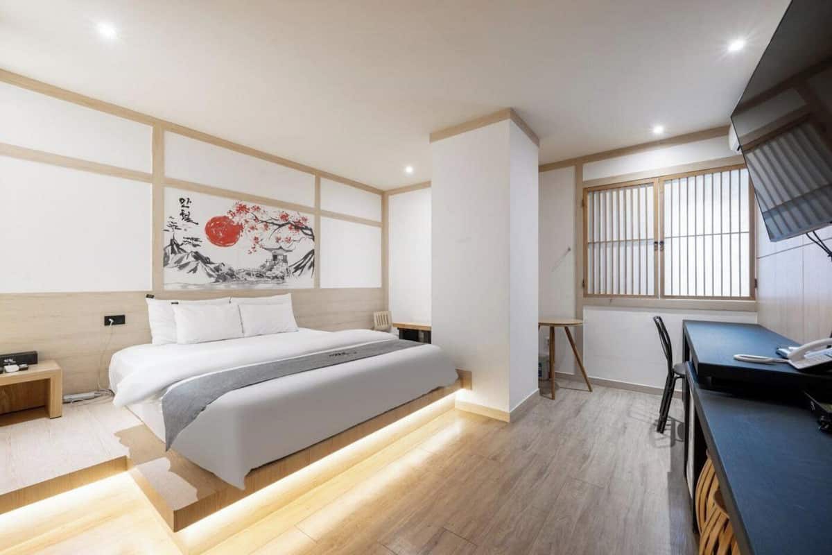 A modern bedroom with a bed, bedside tables, a desk, and a chair.
