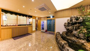 A hotel lobby with a reception desk, a vending machine, a water feature, and a wooden wall. - Daeheung Manwol Hotel (Daejeon)