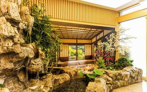 A traditional Japanese-style interior with a rock garden, a small pond with lotus flowers, and a view of a lush garden through sliding doors. - Daeheung Manwol Hotel (Daejeon)