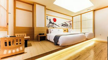 A modern hotel room with a bed, bedside table, and a desk with a chair.