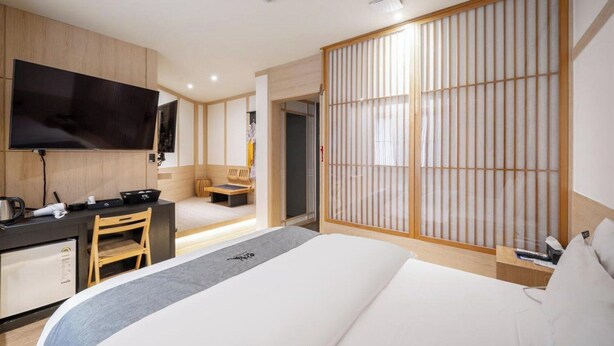 A hotel room with a bed, a desk with a chair, a television, and a sliding shoji screen. - Daeheung Manwol Hotel (Daejeon)