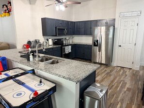 A kitchen with dark cabinets, stainless steel appliances, a granite countertop, and a hockey table. - 4 Bedroom Villa close to Theme Parks sleeps 9 (Clermont)