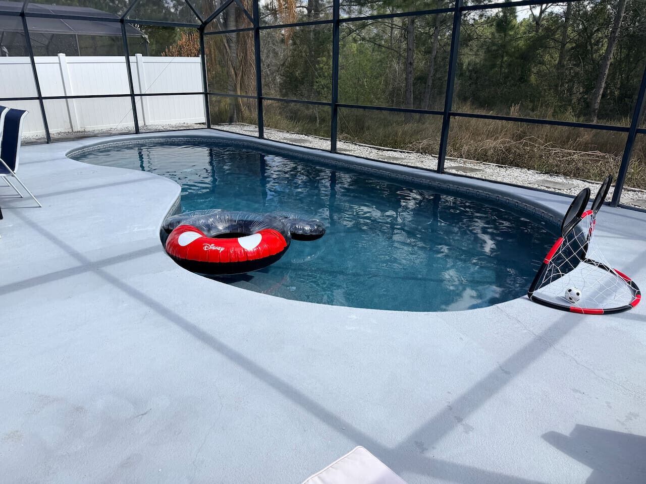 A swimming pool with a diving board, a red inflatable ring, and a small soccer ball on the edge.