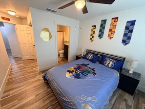 A bedroom with a bed, a ceiling fan, a nightstand, and a bathroom visible through an open door. - 4 Bedroom Villa close to Theme Parks sleeps 9 (Clermont)