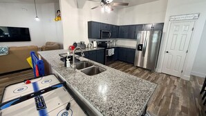 Cozinha moderna com bancadas de granito, eletrodomésticos de aço inoxidável e ventilador de teto.