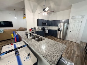 A modern kitchen with granite countertops, stainless steel appliances, and a ceiling fan. - 4 Bedroom Villa close to Theme Parks sleeps 9 (Clermont)