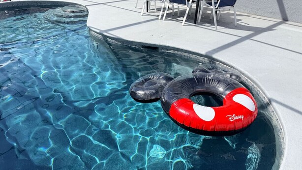 Piscina com água cristalina e dois flutuadores infláveis.