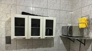 A bathroom with a white air conditioning unit, a microwave on a shelf, and a towel rack with a yellow towel.