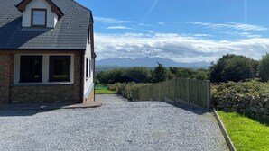 A house with a gravel driveway, a stone wall, and a wooden fence. - Hilltop house (castlemaine co Kerry)