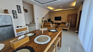 Un salon moderne avec une table à manger en bois, un canapé et un téléviseur.