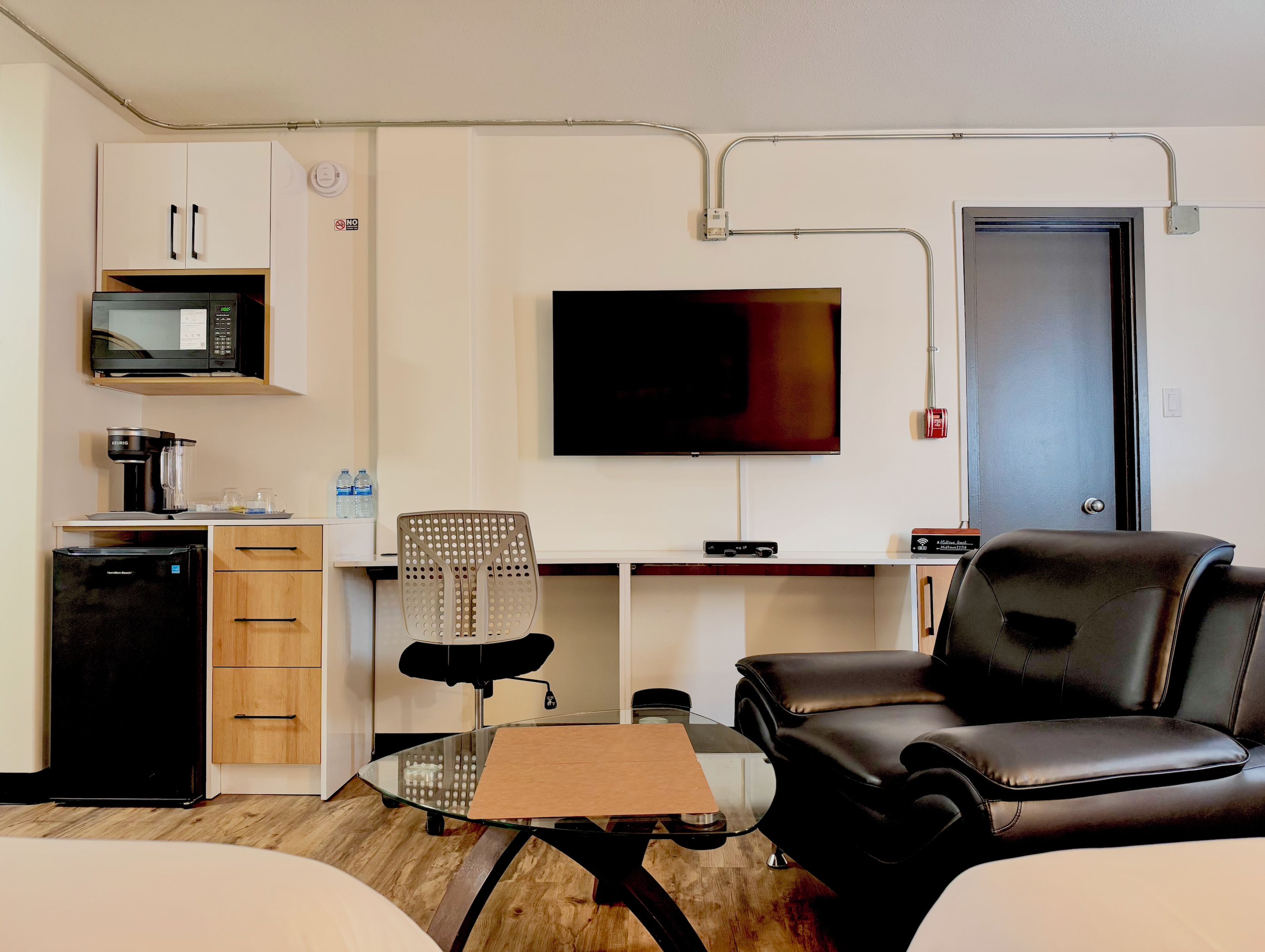 A compact living space with a kitchenette, a flat-screen TV, a dining table, and seating area.