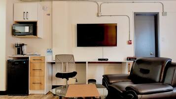 A compact living space with a kitchenette, a flat-screen TV, a dining table, and seating area.