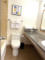 Un baño con inodoro, lavamanos, espejo y toallero.