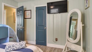 A bedroom with a bed, a dresser, a TV, a mirror, and doors. - Near Beach & Corey Ave! Walkable Snowbird Escape (St Pete Beach)