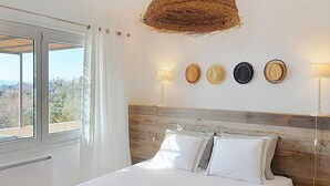 Una camera da letto con un letto, una finestra, un espositore per cappelli a parete e un cesto appeso.